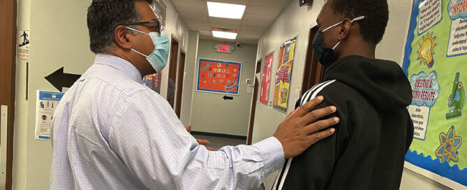 Principal Mathew works one-on-one with a student to resolve a conflict while teaching social skills and reinforcing their application in situ