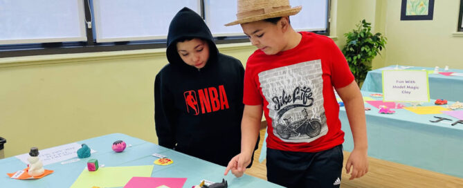 Two young male students reviewing art work at a student art show