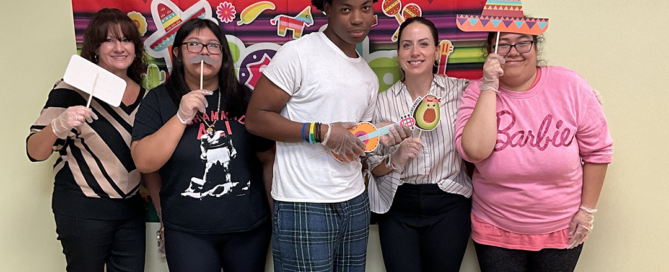 A group of teachers and students posing with Spanish party favors celebrating Hispanic Awareness month